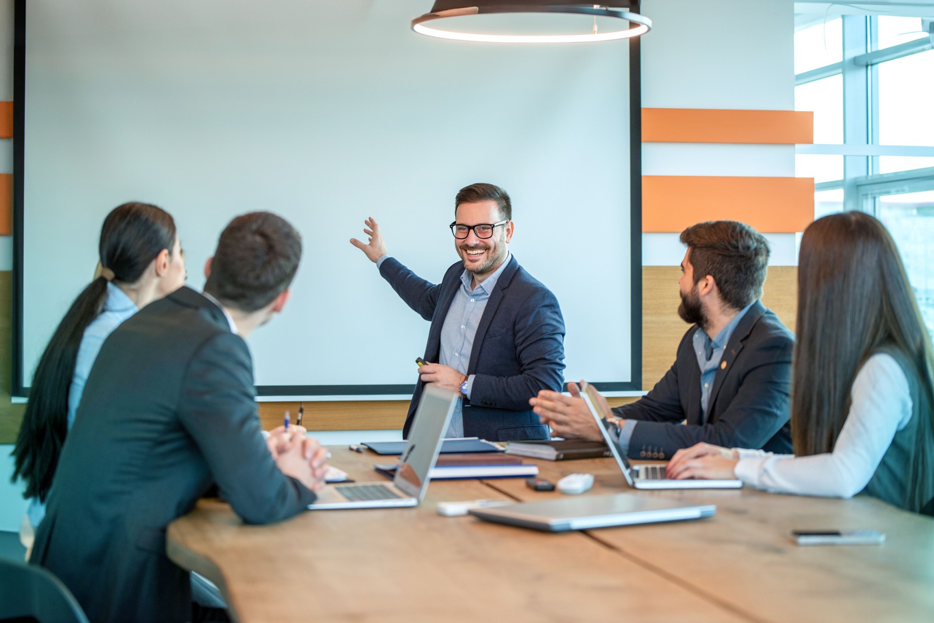 Male presenter giving business presentation on white board at briefing in conference room.